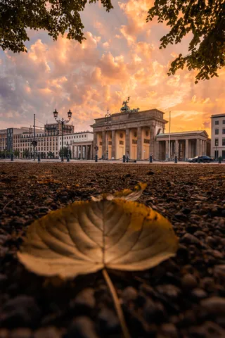 Herbstblatt auf dem Boden vor dem Brandenburger Tor unter leuchtendem Himmel