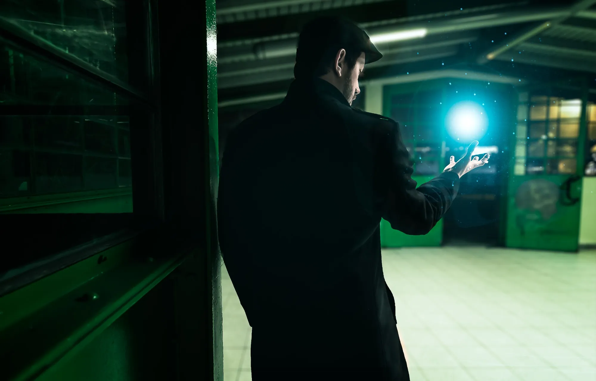 Vincent von hinten in einer dunklen Halle, mit einem leuchtenden Licht in der Hand.